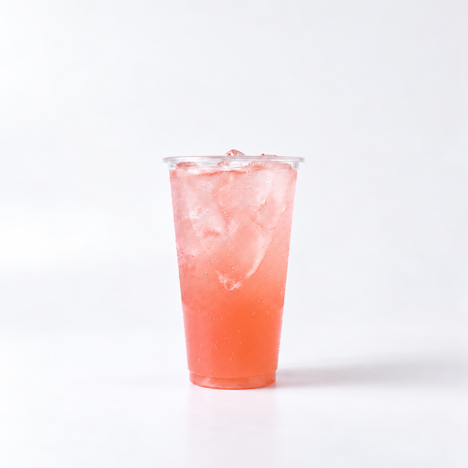 Clear plastic cup filled with an iced pink-orange beverage, condensation visible against a white background.