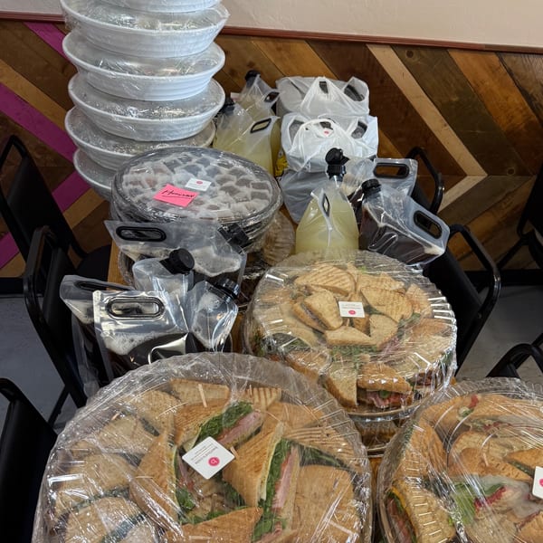 Catering order from Bertha's Cafe with platters of sandwiches, desserts, and drinks.