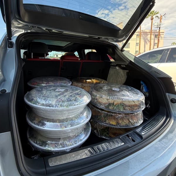 Catering trays from Bertha's Cafe & Catering loaded in the trunk of a car.